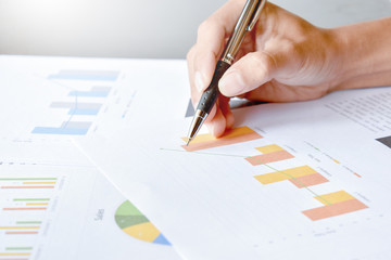 The hand is holding the pen writing business graphs on paper 