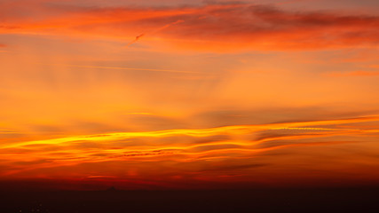 Bergamo, Italy. Fiery sunset over the Po valley and the Alps. Clouds that create light red and orange waves. Fabulous contest. Warm colors