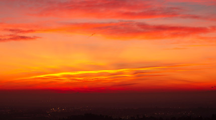 Bergamo, Italy. Fiery sunset over the Po valley and the Alps. Clouds that create light red and orange waves. Fabulous contest. Warm colors