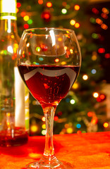 Glass of Red Wine with Wine Bottle in Front of Bokeh Christmas tree