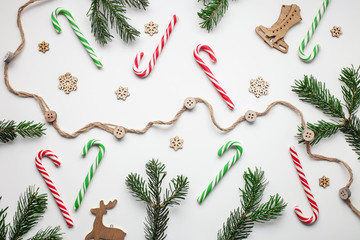 Candy Canes and lollipops with branches fir on a white background. Christmas postcard. Happy New Year concept. Top view. Flat lay