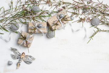 Christmas gifts surrounded by Australian native Melaleuca plants and decorations. Gifts are wrapped with silver ribbon, a silver angel, baubles and glitter finish the Christmas composition off.