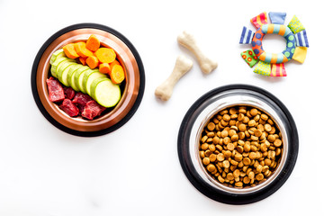 Dog feed - dry food and raw meat - near toy and cheving bones on white background top view copy space