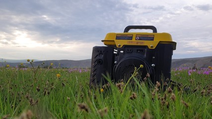Close up of gas diesel mobile portable electricity generator work on grass. Gasoline fuel powered...