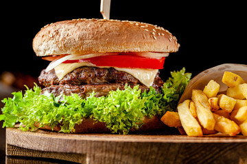 The concept of american cuisine. Italian double king burger with french fries on a wooden board....