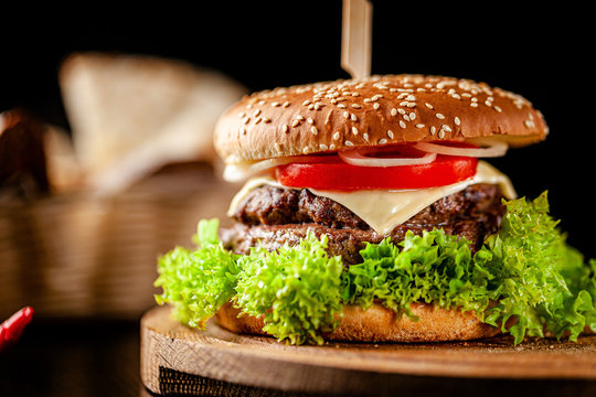 The concept of american cuisine. Italian double king burger with french fries on a wooden board. Serving a burger in a restaurant with a knife. background image, copy space text