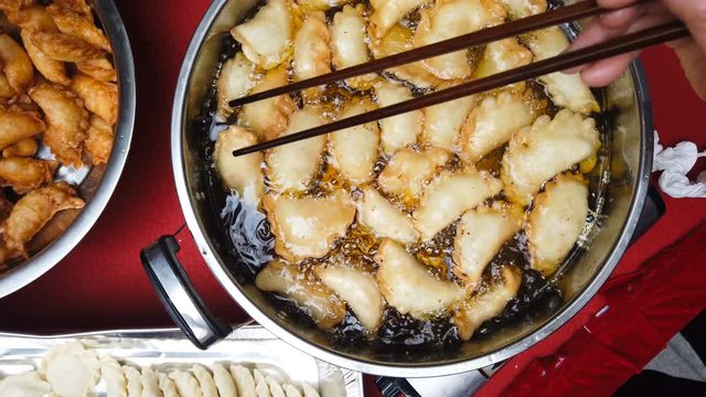 top view frying traditional Chinese Yau Kok Zai or sweet dumpling with some raw ones nearby for Chinese New Year