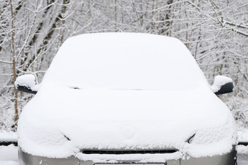 Snow covered car on a city street after snowfall on a winter day