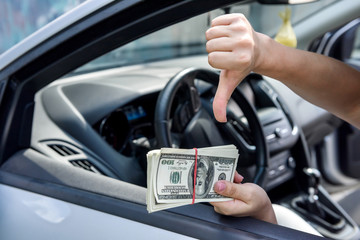 Female hands with dollar bundle on steering wheel close up. Bribery and corruption