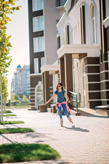 Beautiful stylish girl in sunglasses and a cap skates on a sunny city in the summer. Sports recreation. Healthy lifestyle.