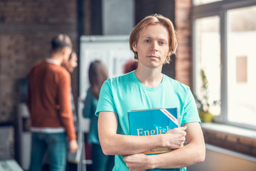 Handsome blue-eyed student holding English grammar book