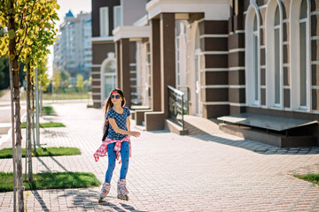 Girl rollerblading on a city street on a bright summer sunny day. Sports recreation. Healthy lifestyle.