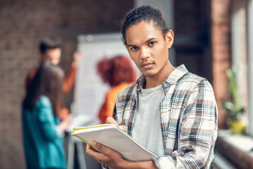 Handsome dark-eyed student feeling concentrated while studying