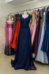 Evening dresses hang on a shelf in store