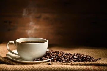 Abwaschbare Fototapete Cafe Tasse Kaffee mit Rauch und Kaffeebohnen auf Leinensack auf altem Holzhintergrund