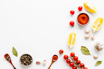 Kitchen frame with spices and food - pepper, garlic, cherry tomatoes - on white background top-down frame copy space