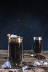Cold coffee with ice and milk on a wooden table