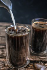 Cold coffee with ice and milk on a wooden table