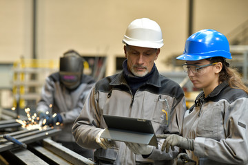 Apprentice working in steelworks plant, with instructor