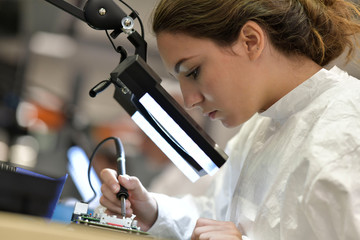 Young woman apprentice working in microelectronics lab