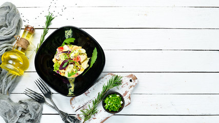 Vegetable salad with chicken, egg and mayonnaise sauce on a black plate. Top view. Free space for...