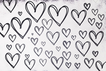 Texture of drawn hearts in black on a white background from flour. Valentine's Day.