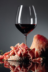 Prosciutto with ciabatta, red wine and thyme on a black background.