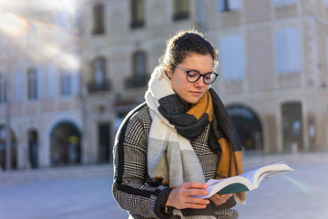 Obraz premium young woman reading a book on the street