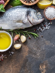 Raw dorado fish with spices and vegetables on the graphite board.