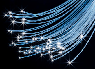 Bundle of optical fibers with lights in the ends. Black background.
