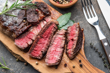 Medium rare Ribeye steak with herbs and a piece of butter on the wooden tray.