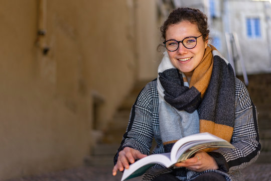 young woman sitting on stairs reading a book