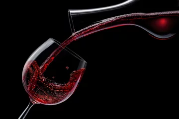  Red wine is poured into a wine glass on a black background. © volff