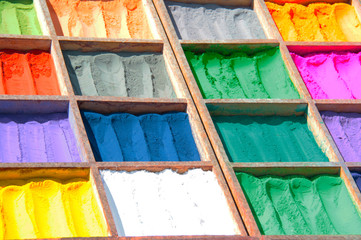 Holi Farbpulver Farbpigmente in Holzschachteln bunt im Sonnenlicht, kleine Dosen aus Metall...