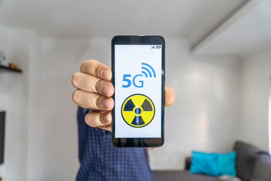 Man showing a smartphone with 5g danger sign on it