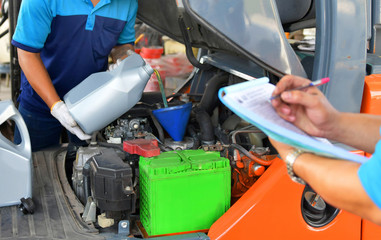 The mechanic is checking the quality and refueling and pouring oil quality into the engine motor...