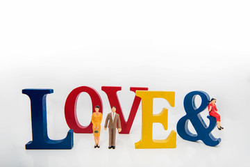 Love triangle. Abstract photo of love and lovers. Big wooden letters with small plastic people figures.