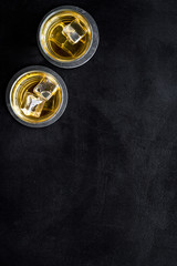 Whiskey with ice. To glasses of strong alcohol drink on black desk top-down frame copy space