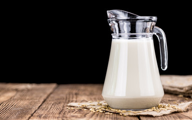 Old wooden table with fresh Oat Milk (close-up shot; selective focus)
