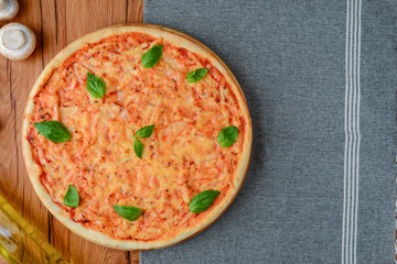 Colorful pizza ingredients: cherry tomatoes, basil, mushrooms, olive oil and pizza on wooden background. Copy space.