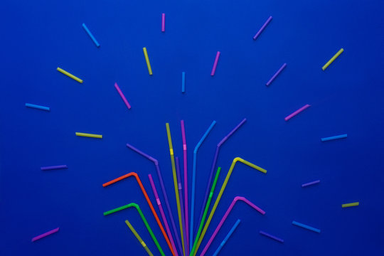 Multi-colored straws for drinking cocktail on blue.