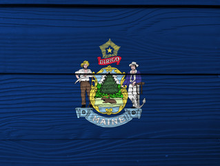 Maine flag color painted on Fiber cement sheet wall background. Maine coat of arms defacing blue field.