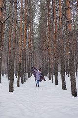 Portrait of a girl in a warm gray coat and burgundy knit scarf in the winter woods.