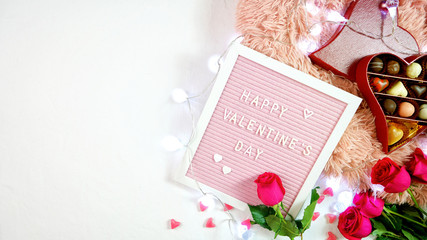 Happy Valentine's Day flat lay overhead with roses, chocolate gift box and letterboard with...