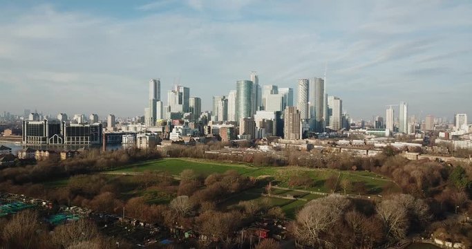 An aerial drone view of Canary Wharf from Millwall Park in a cloudy weather during the daytime.