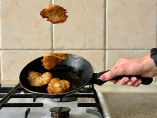 Potato pancakes in the cooking process. Fried pancakes in an old pan, on a gas stove. Cooked pies in a pan in sunflower oil.