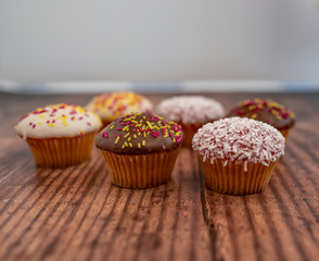  Close and selective focus on a chocolate cupcake among other cupcakes on a wooden background
