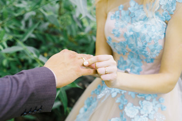 The bride puts a wedding ring on her finger to the groom