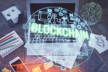 Double exposure of blockchain theme hologram and table with computer background. Concept of bitcoin crypto currency.