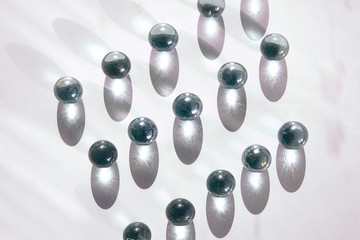 Arrangement of shiny marble balls with long shadows flat lay on white background. Neutral elegant...